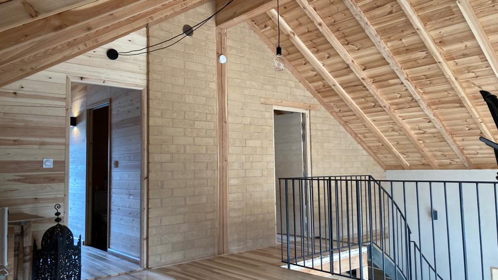finitions interieur dans maison bois paille, enduits terre, mélèze et brique de terre crue.