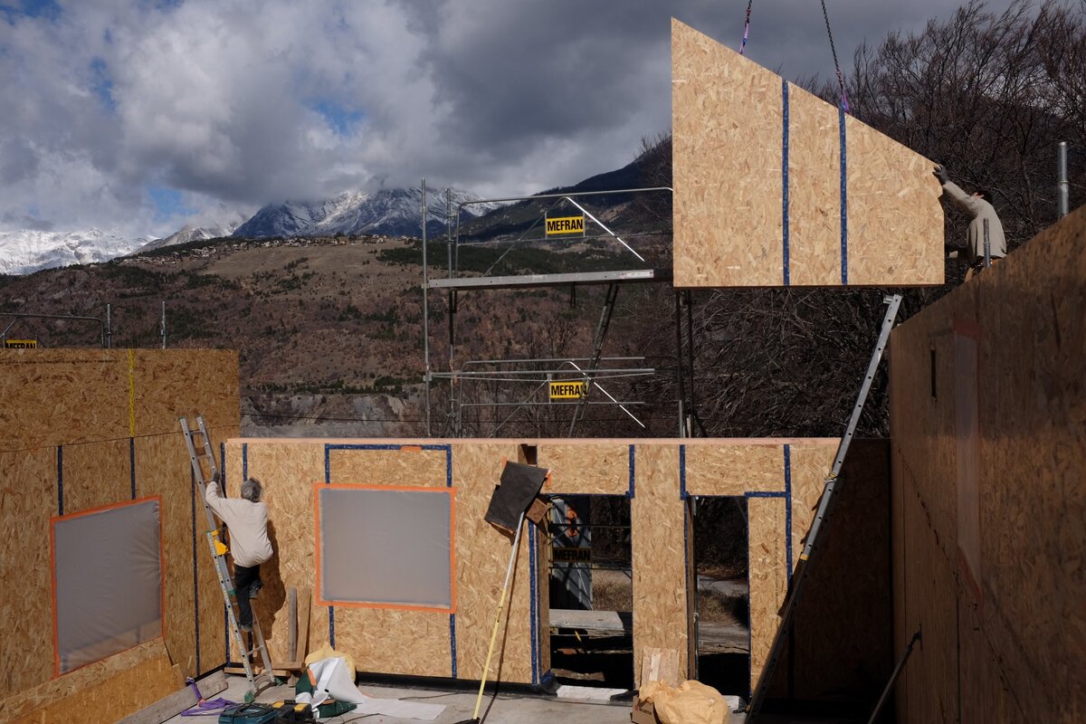 Pose d'un mur ossature bois paille préfabriqué.